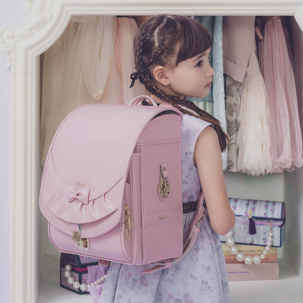 ランドセル リボンフリル パウダーピンク 半かぶせタイプ リリコ かぶせに大胆にあしらわれたフリル、センターに置かれた可憐なリボン ぎゅっと抱きしめたくなる女の子ランドセル