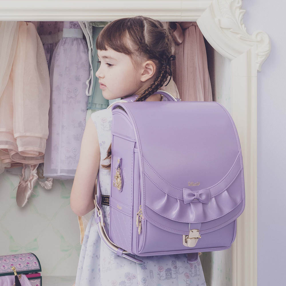 ランドセル リボンフリル シルキーパープル 半かぶせタイプ リリコ かぶせに大胆にあしらわれたフリル、センターに置かれた可憐なリボン ぎゅっと抱きしめたくなる女の子ランドセル
