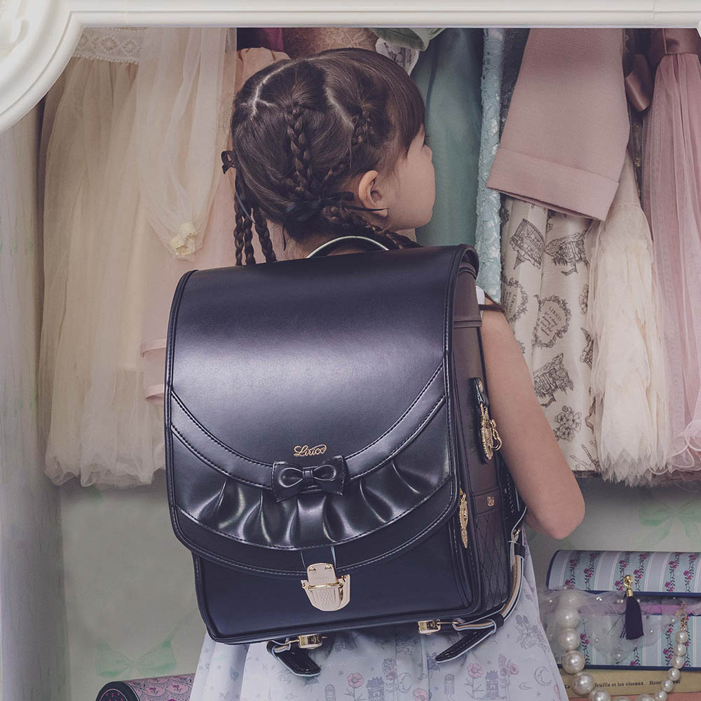 ランドセル リボンフリル ロイヤルノアール 半かぶせタイプ リリコ かぶせに大胆にあしらわれたフリル、センターに置かれた可憐なリボン ぎゅっと抱きしめたくなる女の子ランドセル