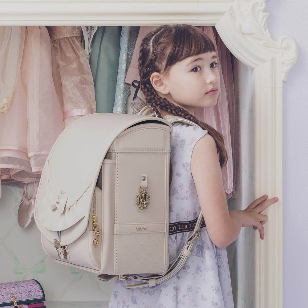 ランドセル リボンフリル ローブアイボリー 半かぶせタイプ リリコ かぶせに大胆にあしらわれたフリル、センターに置かれた可憐なリボン ぎゅっと抱きしめたくなる女の子ランドセル