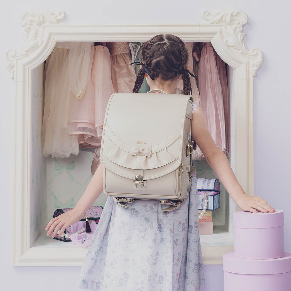 ランドセル リボンフリル ローブアイボリー 半かぶせタイプ リリコ かぶせに大胆にあしらわれたフリル、センターに置かれた可憐なリボン ぎゅっと抱きしめたくなる女の子ランドセル