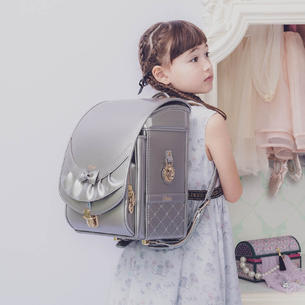 ランドセル リボンフリル パールグレー 半かぶせタイプ リリコ かぶせに大胆にあしらわれたフリル、センターに置かれた可憐なリボン ぎゅっと抱きしめたくなる女の子ランドセル