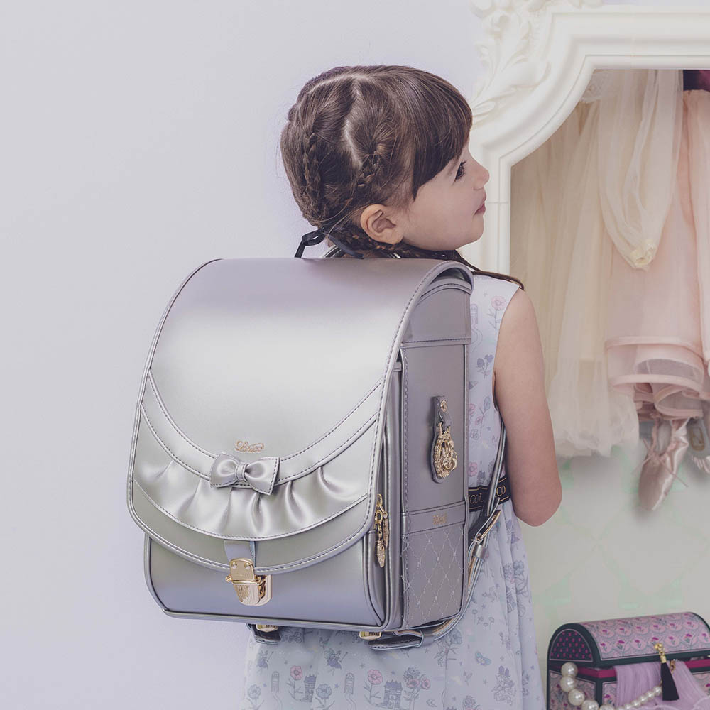ランドセル リボンフリル パールグレー 半かぶせタイプ リリコ かぶせに大胆にあしらわれたフリル、センターに置かれた可憐なリボン ぎゅっと抱きしめたくなる女の子ランドセル