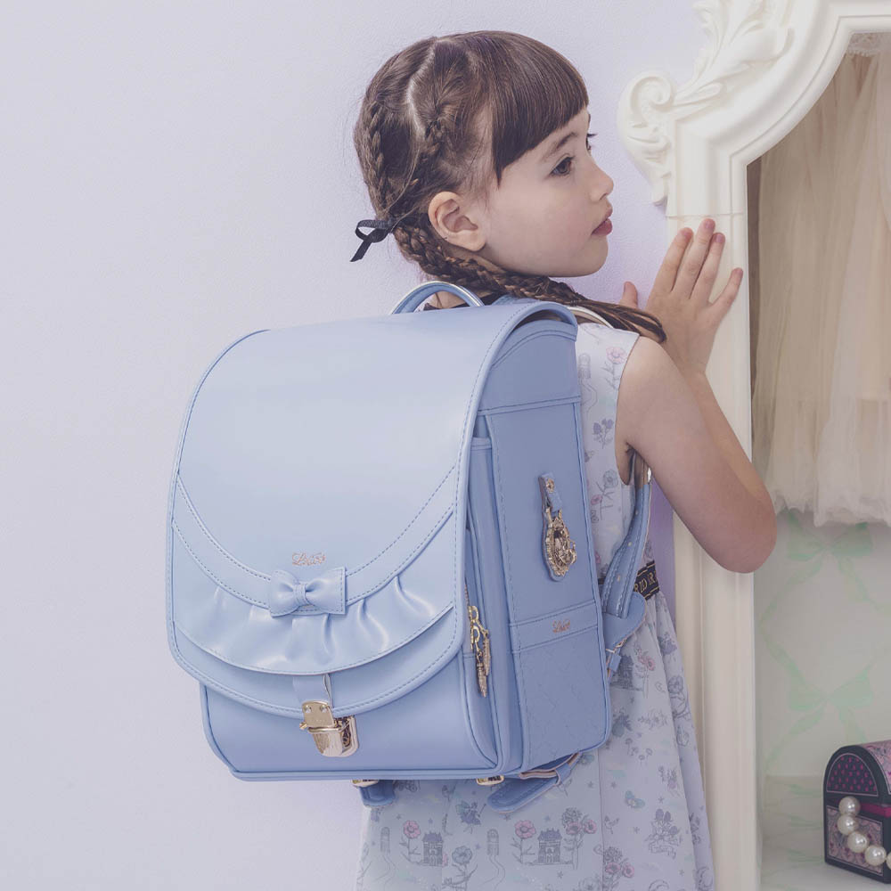 ランドセル リボンフリル ペールブルー 半かぶせタイプ リリコ かぶせに大胆にあしらわれたフリル、センターに置かれた可憐なリボン ぎゅっと抱きしめたくなる女の子ランドセル