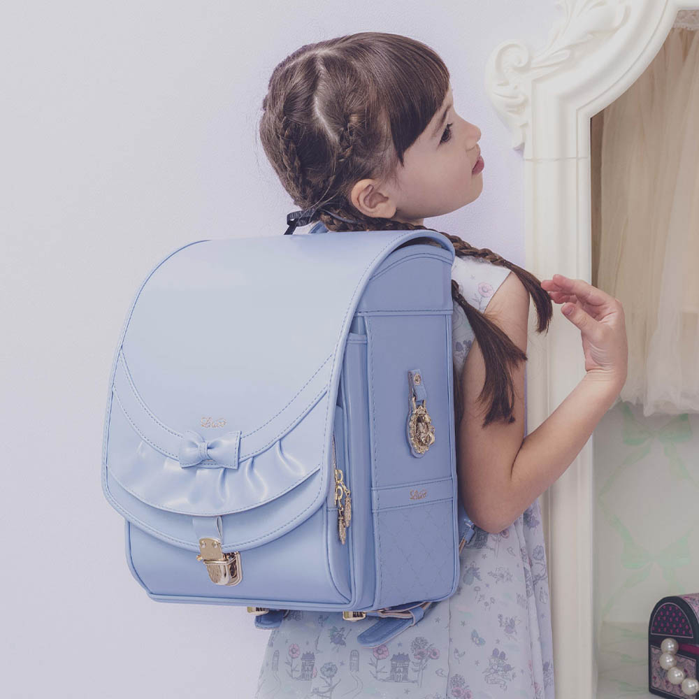 ランドセル リボンフリル ペールブルー 半かぶせタイプ リリコ かぶせに大胆にあしらわれたフリル、センターに置かれた可憐なリボン ぎゅっと抱きしめたくなる女の子ランドセル